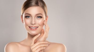 A woman touching her cheek after getting dermal fillers in West Des Moines